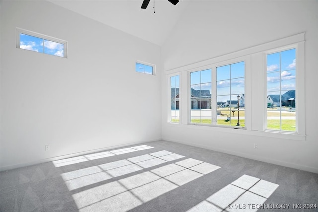 empty room with ceiling fan, carpet floors, a healthy amount of sunlight, and high vaulted ceiling