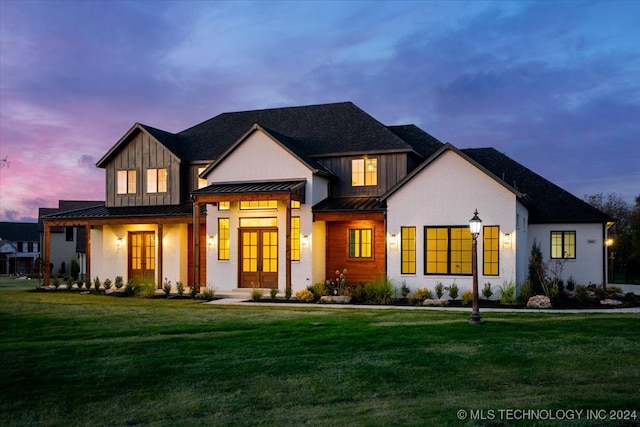 modern farmhouse with a standing seam roof, french doors, a front lawn, board and batten siding, and brick siding