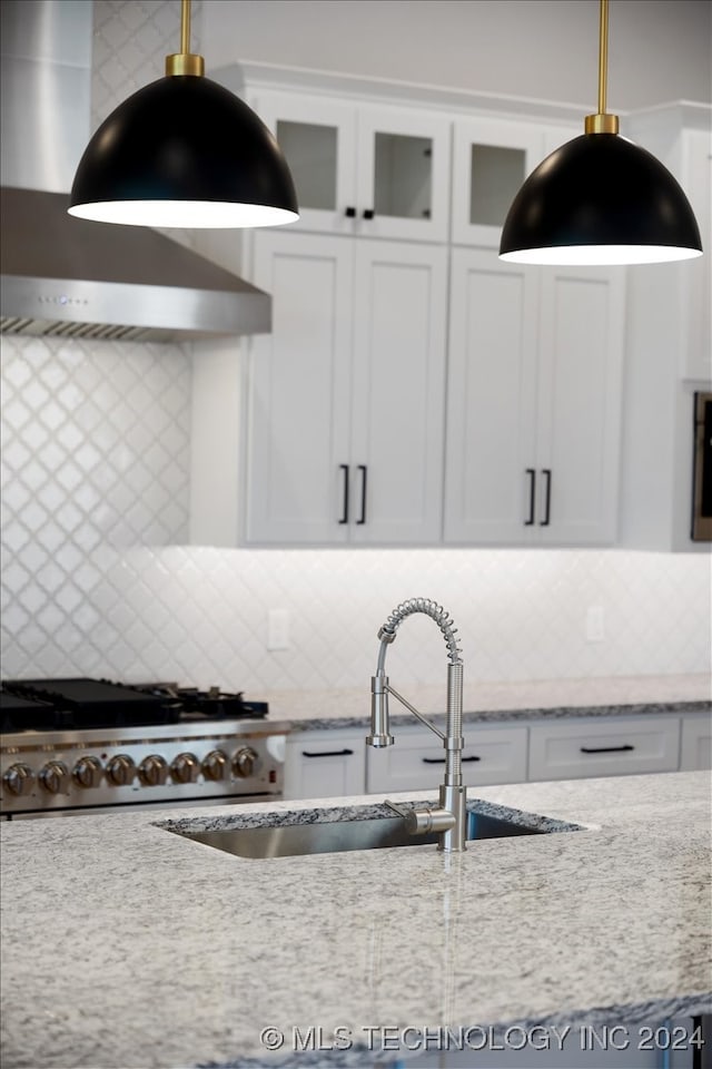 kitchen with white cabinetry, light stone countertops, hanging light fixtures, tasteful backsplash, and stainless steel range oven