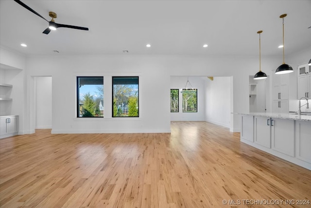 unfurnished living room with ceiling fan, ornamental molding, sink, and light hardwood / wood-style flooring