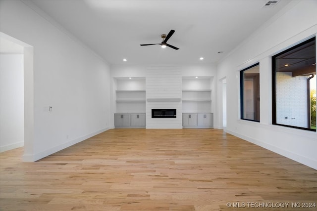 unfurnished living room featuring light hardwood / wood-style flooring, built in features, ceiling fan, and crown molding