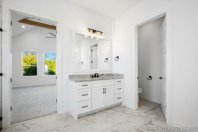 bathroom with ceiling fan, vanity, lofted ceiling with beams, and toilet