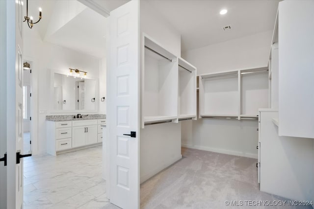 spacious closet with a notable chandelier, sink, and light carpet