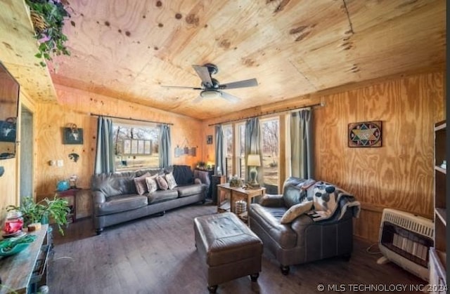 living room with dark hardwood / wood-style flooring, heating unit, ceiling fan, wooden walls, and wooden ceiling