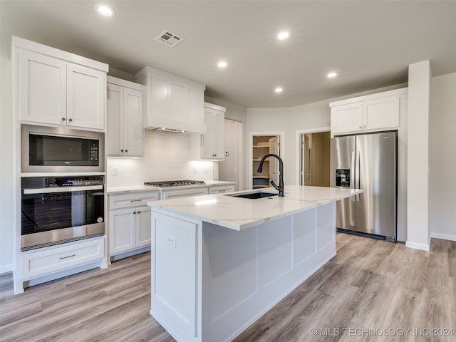 kitchen with light hardwood / wood-style flooring, sink, appliances with stainless steel finishes, and an island with sink