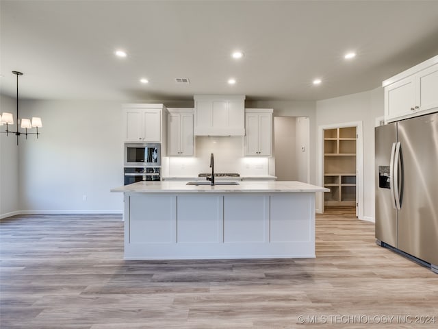 kitchen with pendant lighting, white cabinetry, stainless steel appliances, and a kitchen island with sink