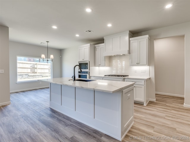 kitchen featuring a center island with sink, white cabinetry, and appliances with stainless steel finishes