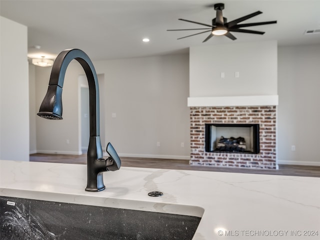 interior space featuring ceiling fan, sink, hardwood / wood-style flooring, and a brick fireplace