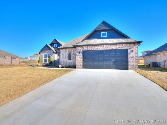 view of front of property with a garage, a front lawn, and central air condition unit