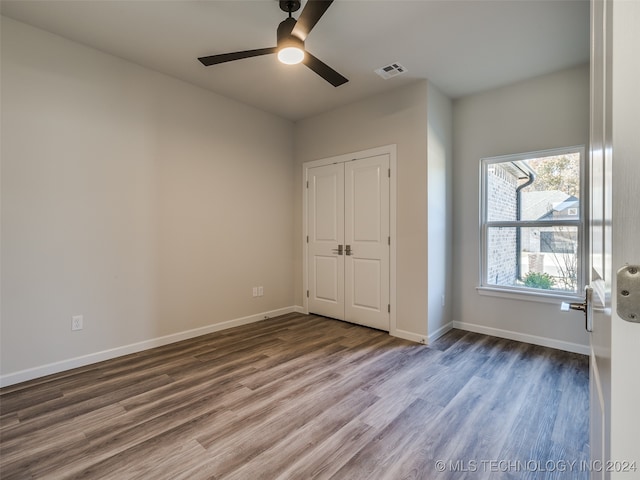 unfurnished bedroom with ceiling fan, a closet, and hardwood / wood-style flooring