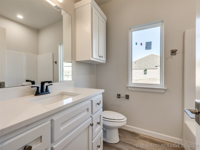 bathroom featuring wood-type flooring, vanity, toilet, and plenty of natural light