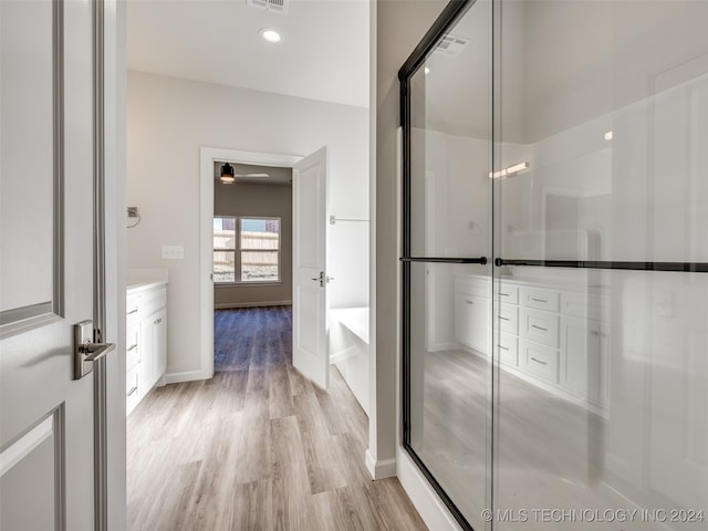 bathroom with hardwood / wood-style floors, vanity, and a shower with shower door