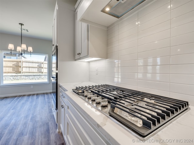 kitchen with backsplash, dark hardwood / wood-style floors, appliances with stainless steel finishes, light stone counters, and white cabinetry