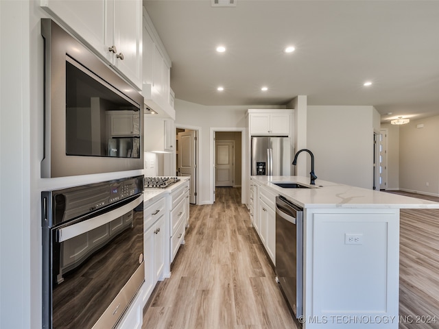 kitchen featuring a center island with sink, sink, light hardwood / wood-style flooring, white cabinetry, and stainless steel appliances