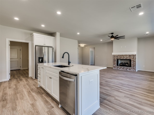 kitchen featuring white cabinetry, sink, an island with sink, and light wood-type flooring