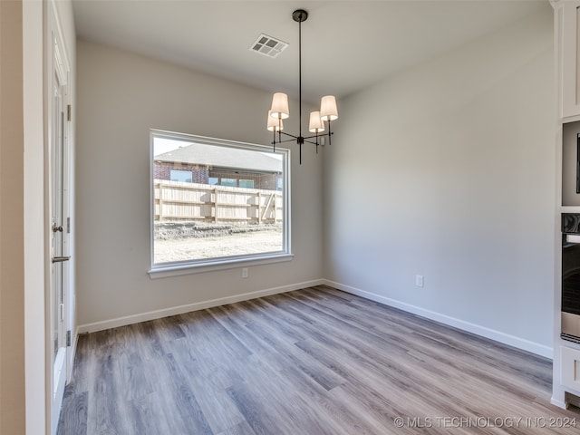 unfurnished dining area featuring light hardwood / wood-style flooring and a notable chandelier