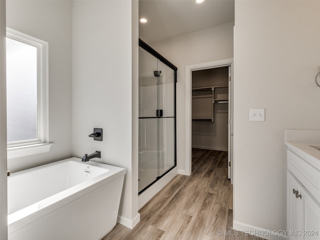 bathroom with hardwood / wood-style floors, vanity, and separate shower and tub