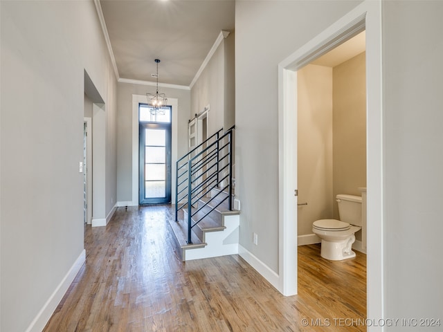 foyer entrance with a chandelier, light wood-type flooring, and ornamental molding