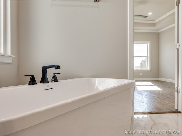 bathroom with wood-type flooring, a tub, and crown molding