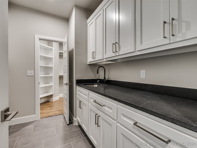 kitchen featuring light tile patterned floors, white cabinetry, and sink