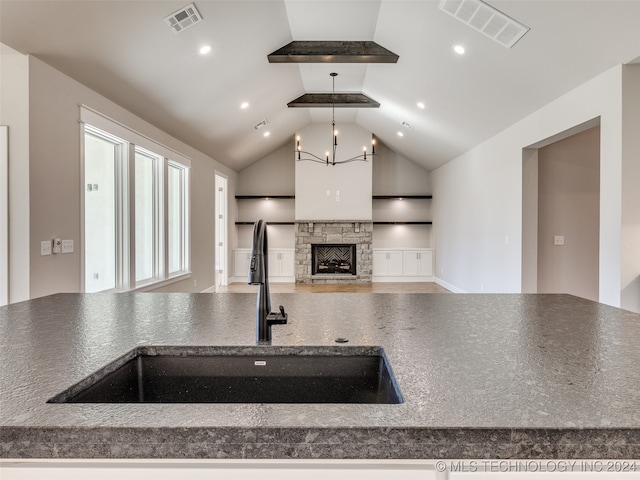 kitchen with pendant lighting, lofted ceiling, an inviting chandelier, sink, and a fireplace