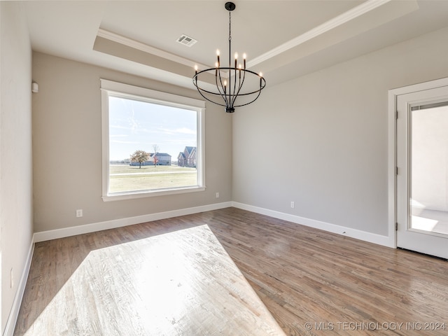 spare room featuring a tray ceiling, hardwood / wood-style floors, and a chandelier