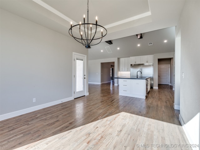 kitchen with a center island with sink, a chandelier, white cabinets, light hardwood / wood-style floors, and hanging light fixtures