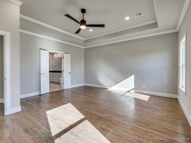 empty room featuring hardwood / wood-style floors, ceiling fan, crown molding, and a tray ceiling