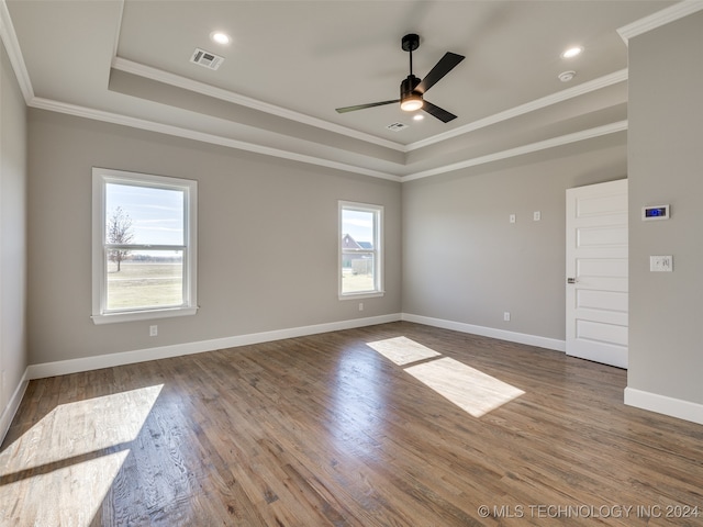 empty room featuring wood-type flooring, a tray ceiling, plenty of natural light, and ornamental molding