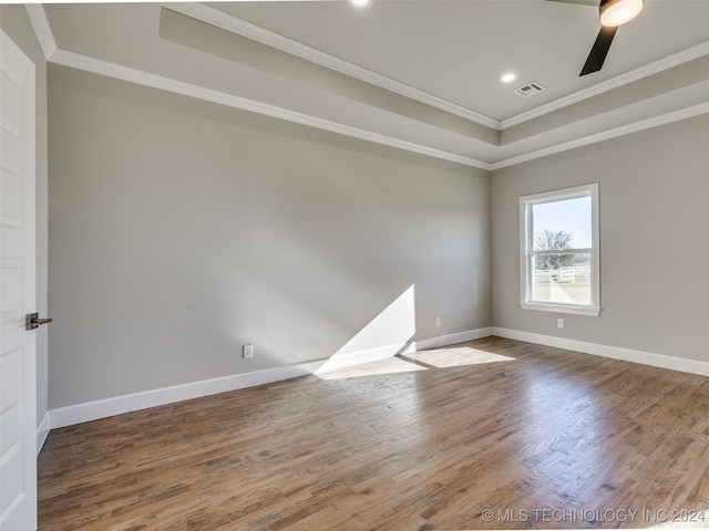 empty room with ceiling fan, a raised ceiling, wood-type flooring, and crown molding