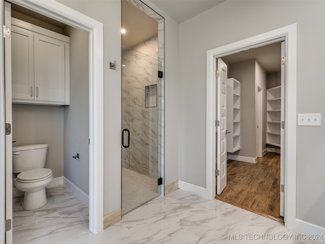 bathroom with hardwood / wood-style flooring, toilet, and walk in shower