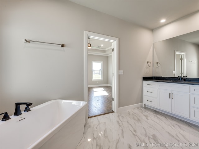 bathroom with vanity, hardwood / wood-style flooring, crown molding, and a bathing tub