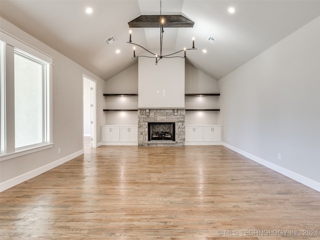 unfurnished living room with a notable chandelier, a fireplace, high vaulted ceiling, and light hardwood / wood-style flooring