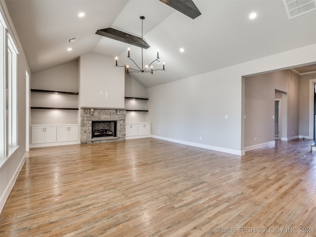 unfurnished living room with lofted ceiling with beams, a stone fireplace, built in shelves, light wood-type flooring, and a chandelier