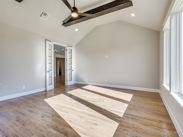 unfurnished bedroom featuring french doors, ceiling fan with notable chandelier, hardwood / wood-style flooring, and vaulted ceiling