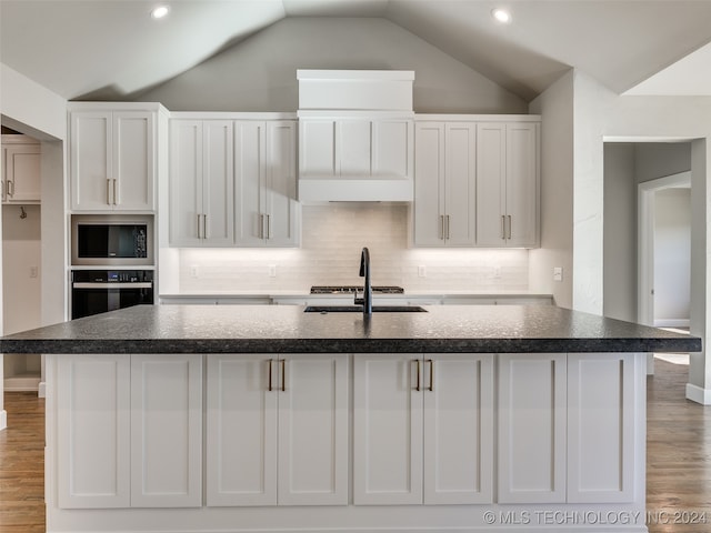 kitchen featuring white cabinets, light wood-type flooring, appliances with stainless steel finishes, and vaulted ceiling