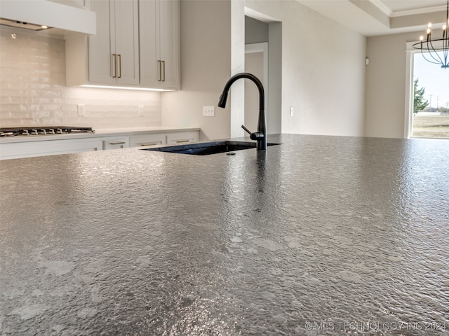 kitchen featuring decorative backsplash, sink, white cabinets, and stainless steel gas stovetop