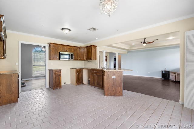 kitchen with crown molding, ceiling fan with notable chandelier, a tray ceiling, a breakfast bar area, and kitchen peninsula