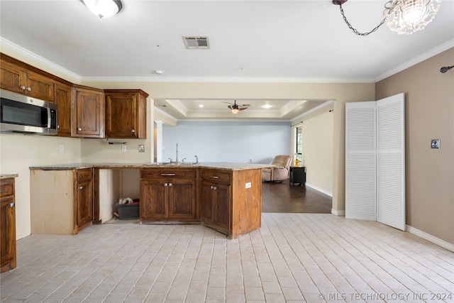 kitchen with light hardwood / wood-style floors, light stone countertops, ornamental molding, sink, and a raised ceiling