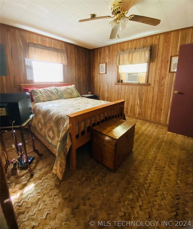 bedroom featuring ceiling fan, dark carpet, and wood walls