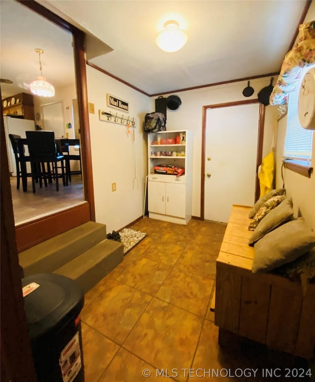 interior space with decorative light fixtures, tile patterned floors, and ornamental molding