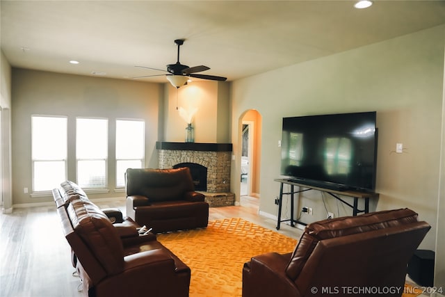 living room featuring a fireplace, light wood-type flooring, and ceiling fan