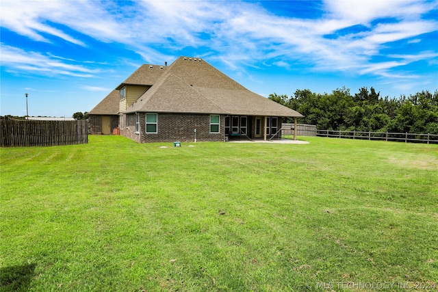 rear view of house with a patio and a yard