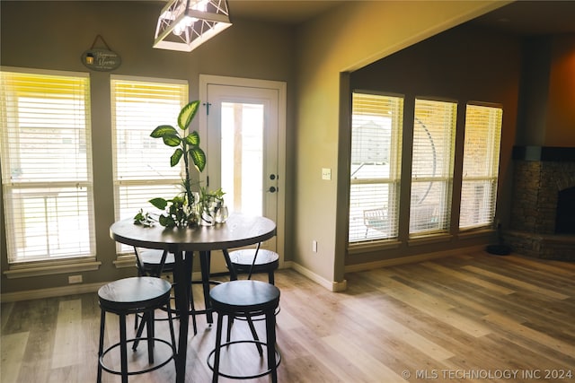 dining room featuring a stone fireplace and wood-type flooring