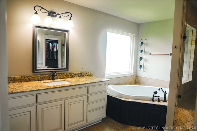 bathroom with tile floors, a relaxing tiled bath, and vanity