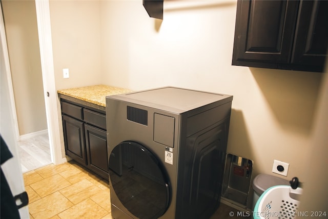 laundry area featuring washer / clothes dryer, cabinets, and light tile floors