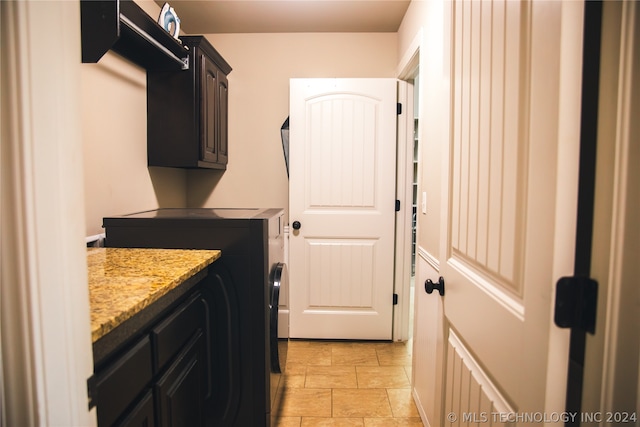 washroom featuring cabinets, washing machine and dryer, and light tile floors