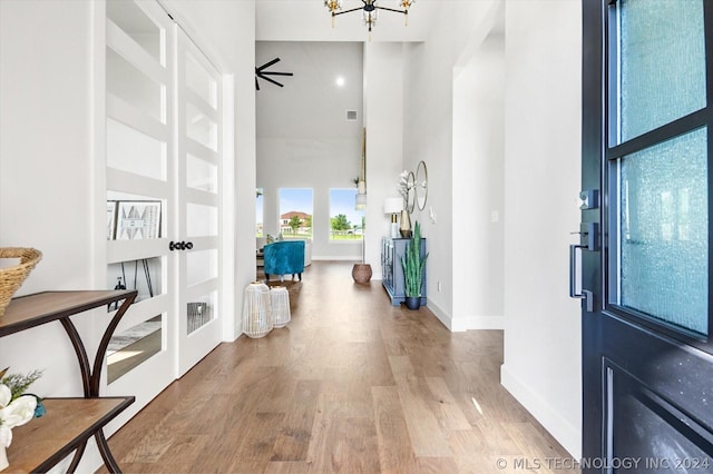 entryway featuring a towering ceiling, a chandelier, and light hardwood / wood-style floors