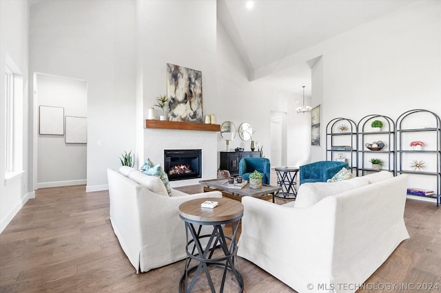 living room featuring a fireplace, hardwood / wood-style flooring, a chandelier, and high vaulted ceiling