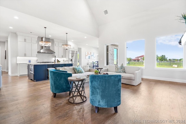 living room with light wood-type flooring and high vaulted ceiling